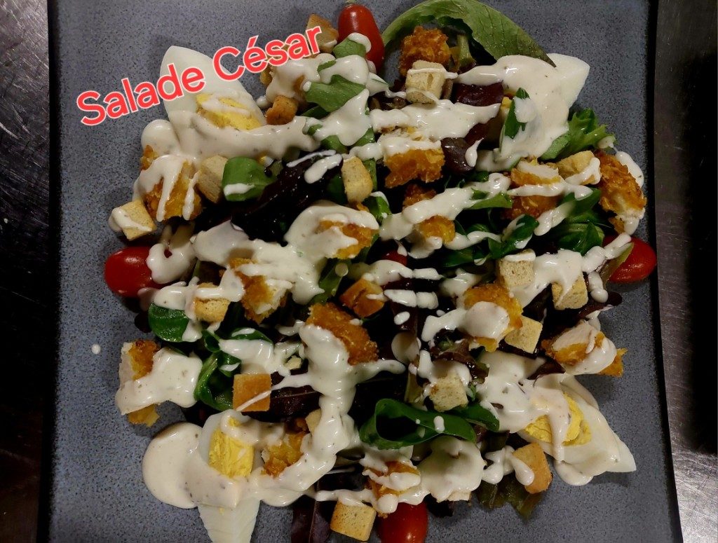 Une salade composée généreuse, avec des croûtons et une sauce blanche